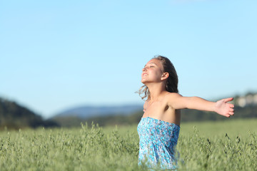 Beautiful woman breathing with raised arms in a green oat meadow