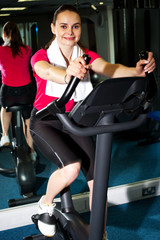 Fototapeta na wymiar Athletic woman cycling at the gym