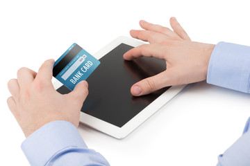 Man's hand holding a credit card over a tablet computer and the