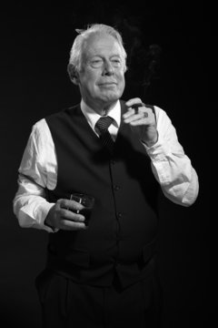 Retro senior business man with whisky smoking cigar. Black and w