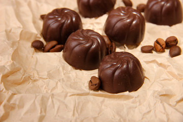 Chocolate candies and coffee beans, on beige paper background