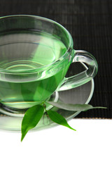 Transparent cup of green tea on bamboo mat, isolated on white