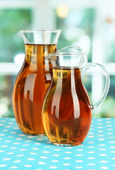 Apple juice in pitchers on table in room