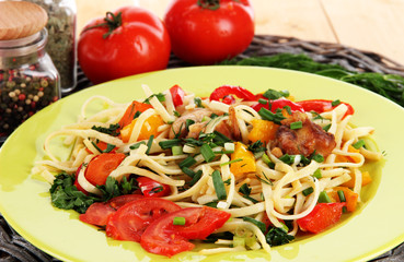 Noodles with vegetables on plates on wooden background close-up