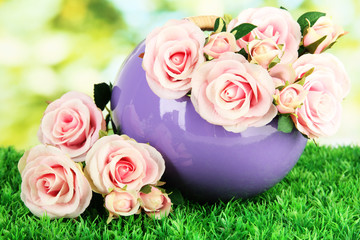 Pot with flowers on the grass on the nature background