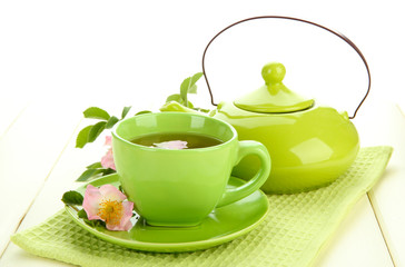 Cup and teapot of herbal tea with hip rose flowers