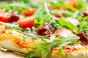 Closeup of pizza with parma ham and arugula