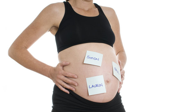 Bauch einer Schwangeren mit Namens-Zettelchen fuer Bubennamen