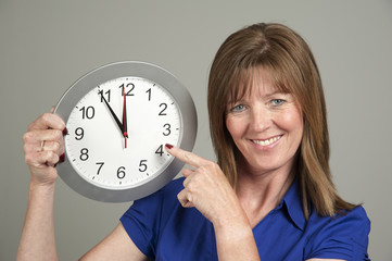 Woman with surprised expression holding a clock
