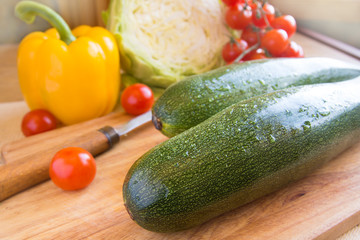 Green ripe zucchini on a wooden background with vegetables