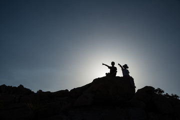 Two children pointing, sitting on rock