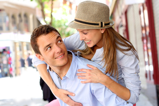Man giving piggyback ride to girlfriend in town