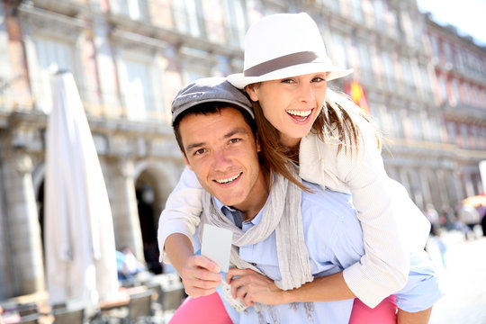 Cheerful couple holding visitor pass of Madrid capital