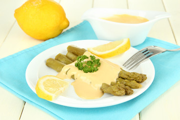 Asparagus on plate, on wooden background