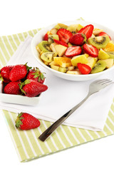 Useful fruit salad of fresh fruits and berries in bowl isolated