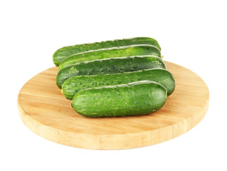 Tasty green cucumbers on wooden cutting board, isolated on