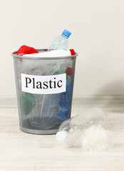 Assorted trash in bucket on room background