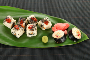 Tasty Maki sushi - Roll on green leaf on wooden table close-up