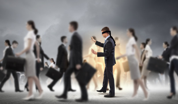 Businessman in blindfold among group of people