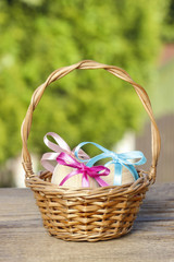 Fototapeta na wymiar Basket of easter eggs on rustic wooden table in sunny spring gar