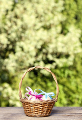 Basket of easter eggs on rustic wooden table in sunny spring gar