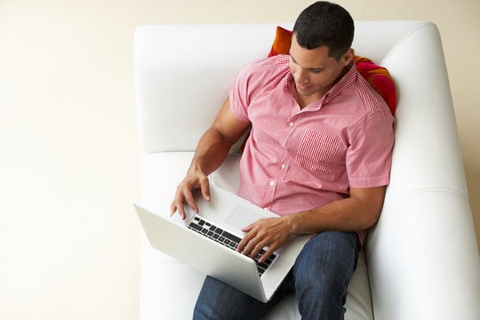 Overhead View Of Man Relaxing On Sofa Using Laptop