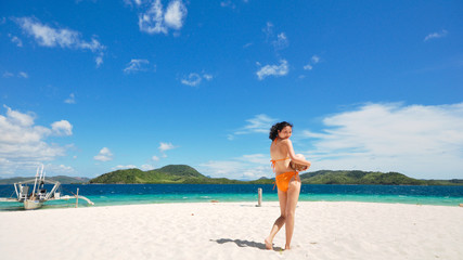 Fototapeta na wymiar beautiful bikini girl holding coconut looks back on white beach