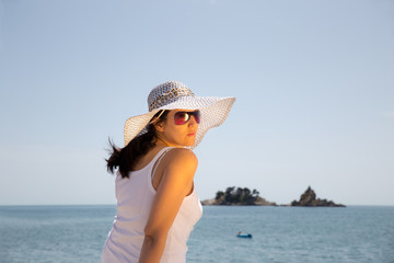 Young woman sitting on the beach looking at the sea and sky.