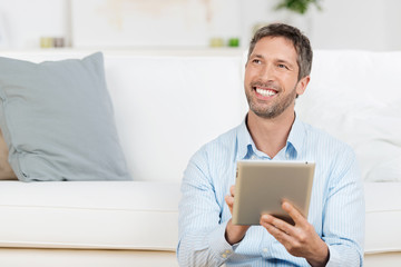 lachender mann mit tablet zu hause