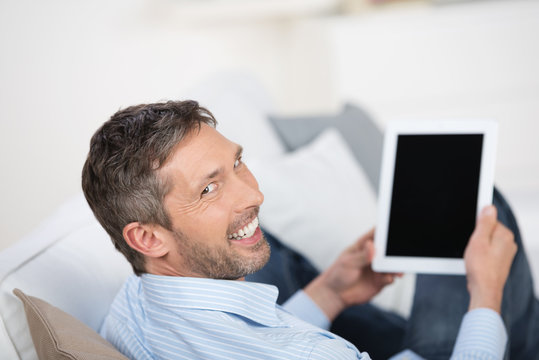 lächelnder mann liest zuhause am tablet