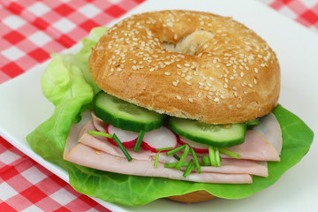 Bagel with ham, lettuce, cucumber and radish, close up