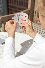 Senior woman playing card game outdoor in garden.