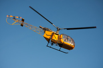 Flying yellow helicopter on blue sky