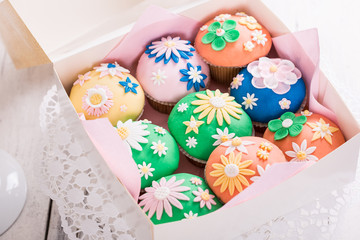 Fototapeta na wymiar Bunte Cupcakes mit Blütendeko verpackt