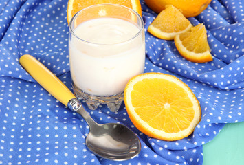 Delicious yogurt in glass with orange on blue tablecloth