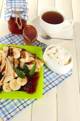 Pancakes with banana on plate on wooden background