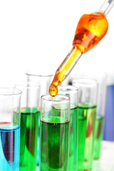 Laboratory pipette with drop of color liquid over glass test