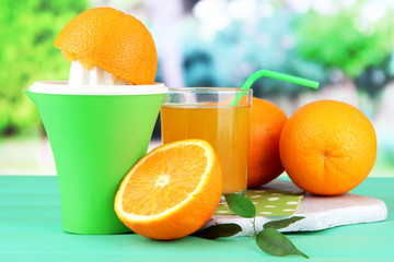 Citrus press, glass of juice and ripe oranges