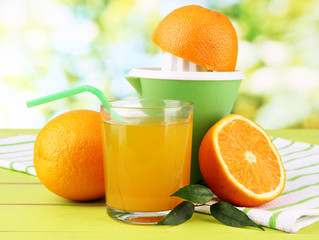 Citrus press, glass of juice and ripe oranges