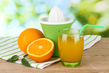 Fototapeta na wymiar Citrus press, glass of juice and ripe oranges