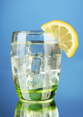 Glass of water and ice on blue background