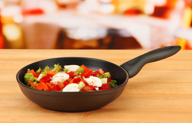 Vegetable ragout in pan,  on wooden table on bright background
