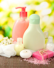 Cosmetics bottles and natural handmade soap on green background
