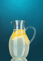 Lemonade in pitcher on blue background