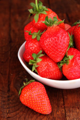 Fresh strawberry in bowl on wooden background