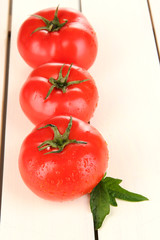 Fresh tomatoes on white wooden background