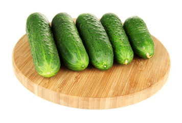 Tasty green cucumbers on wooden cutting board, isolated on