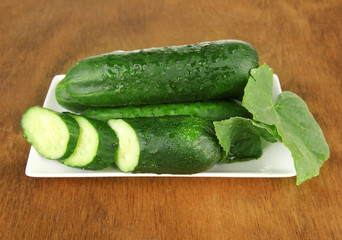 Tasty green cucumbers on color napkin, wooden background