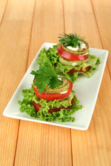 Tasty roasted marrow and tomato slices with salad leaves,