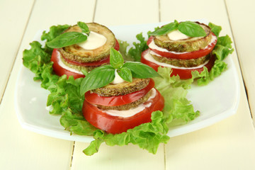 Tasty roasted marrow and tomato slices with salad leaves,